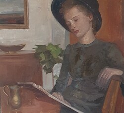 Zu sehen ist eine junge Frau mit Hut. Sie sitzt an einem Tisch und liest in einem dünnen Buch. Vor ihr auf dem Tisch steht ein kleiner Krug. Im Hintergrund ist ein Zimmer zu sehen mit Kommode, Bild und Pflanze 