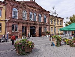 Die Ideengeberin, ein Ehrenamtlicher und EBM Herr Schöneboom vor dem geöffneten Öffentlichen Kühlschrank stoßen 2024 mit Sekt auf die Eröffnung an