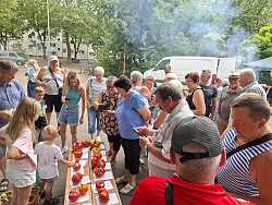 Gruppe von Menschen steht um einen Tisch mit verschiedenen großen Tomaten im Freien bei Tageslicht.