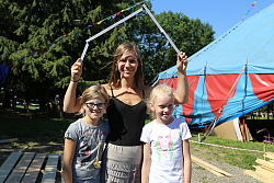 Das Bild zeigt eine Jugendliche, die einen Zollstock wie einer Art Dach über sich und zwei Mädchen hält, die rechts und links neben ihr stehen.