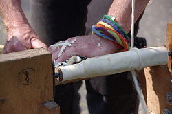 Das Bild zeigt Hände, die ein eingespanntes Stück Holz drechseln.
