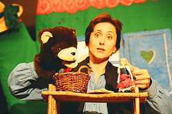 Eine Frau spielt mit der Handpuppe - einem Bären - und einem kleinen Puppenmädchen Theater.