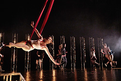 Eine Trapezkünstlerin schwebt im Vordergrund.