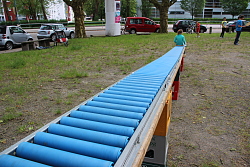 Das Bild zeigt ein Mädchen, das eine blaue Rollen-Rutsche hinunterrutscht.