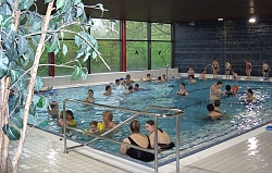Das Bild zeigt das Nichtschwimmer-Becken im Hallenbad mit etlichen Badegästen darin.