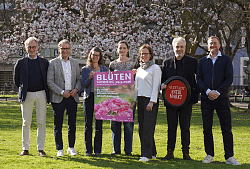 Sieben Personen mit einem Plakat zum Blütensonntag in Lahr, im Hintergrund blühende Bäume