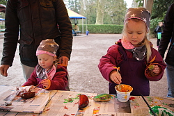 Das Bild zeigt zwei Mädchen, die mit ihrem Vater Steine bemalen.