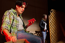 Eine Frau sitzt im Vordergrund und hält einen Brief in der Hand. Im Hintergrund steht eine weitere Frau.