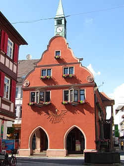 Historisches rotes Gebäude mit bunten Blumen vor den Fenstern