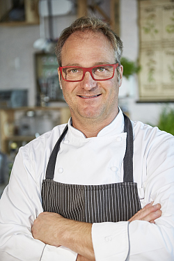 Das Foto zeigt einen Mann. Es handelt sich um einen Koch, der auch diese typische Kleidung trägt. 