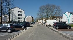 Ausbaufortschritt der Straße Kanadaring Anfang April 2020. Neue Straße mit parkenden Autos links und rechts, dahinter Wohnblocks