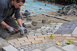 Auszubildende des Bau- und Gartenbetriebs Lahr setzen Steine und Platten für das Hundertwasser-Beet bei der Chrysanthema
