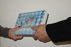 Foto zeigt die rechte Hand einer Frau und die linke Hand eines Mannes, die ein Buch halten.