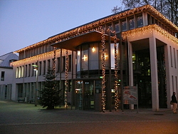 Das Bild zeigt das Bürgerbüro mit Weihnachtsbeleuchtung und einem Weihnachtsbaum links vor dem Eingang.