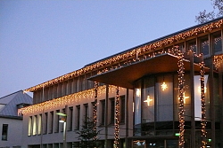 Das Bild zeigt das Bürgerbüro mit Weihnachtsbeleuchtung und einem Weihnachtsbaum links vor dem Eingang.