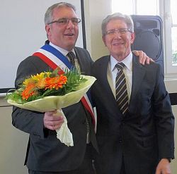 Das Bild zeigt Jean-Marc Willer mit Blumenstrauß und französischer Schärpe und Dr. Wolfgang G. Müller Arm in Arm.
