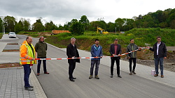 Symbolischer Schnitt: Baubürgermeister Tilman Petters, Nicolas Knäble von der Firma Knäble Straßenbau und Uwe Schade vom Erschließungsträger STEG (von links) schneiden ein Absperrband durch, das über die Straße gespannt wird.