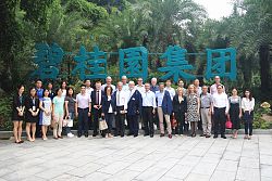 Die Stadt Lahr und die Freiburg Wirtschafr Messe und Touristik GmbH sind Mitglieder der ISA. Das Bild zeigt die Delegation und die ISA-Mitglieder bei einem Gruppenbild bei dem Unternehmen Country Garden. Im Hintergrund sieht man blaue chinesiche Schriftzeichen in einer parkähnlichen Anlage. 