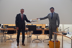 Das Foto zeigt zwei Männer bei einer Geschenkübergabe.