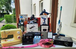 Ein Tisch, auf dem verschiedene Gegenstände aufgebaut sind, wie Nähmaschine, Beamer, Tiptoi, Akkuschrauber. 
