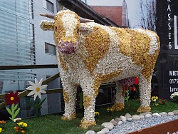 Blütenwagen mit dem Motiv einer Kuh, die komplett mit Blüten beklebt ist.