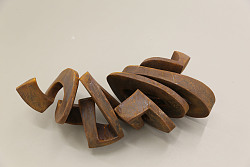 Gewundene Figur aus rostigem Stahlblech vor hellem Hintergrund.