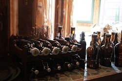 Das Foto zeigt zahlreiche spezielle Bierflaschen aus der Dammenmühle, teilweise liegend in einem Regal.