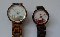 Das Bild zeigt die neue Lahrer City-Watch aus Holz, links für Männder und rechts, etwas kleiner, für Frauen. Im unteren Teil des Ziffernblatts sieht man die markanten Motive aus Lahr.