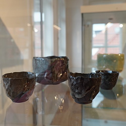 Das Bild zeigt verschiedene dunkelgraue japanische Schälchen in einer Glasvitrine. 