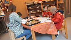 Eine Erzieherin mit drei Kindern am Malen 