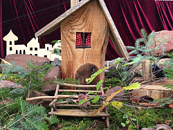 Das Foto zeigt ein kleines schiefes Häuschen. Es gehört der kleinen Hexe und ist deshalb mit viel Moos geschmückt.