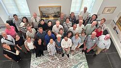 Das Foto zeigt die Lahrer Delegation beim Besuch in Dole im Museum der Schönen Künste. Auf dem Boden liegt ein Teppich mit dem Abdruck des Stadtplans der Stadt Dole. An den Wänden sind verschiedene Gemälde in goldenem Rahmen zu sehen.