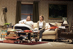 Ein Schauspieler und eine Schauspielerin auf einem Sofa im Wohnzimmer