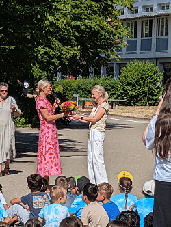 Senja Dewes übergibt bei einem Fest auf einem Schulhof einen Blumenstrauß an Kathrin Seidel 