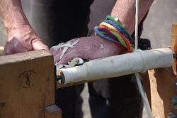Ein Holzpfosten wird an einer Drechselbank rund geschliffen.