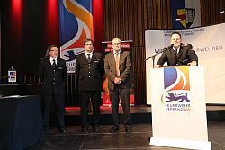 Michael Wegel, Vizepräsident des Landesfeuerwehrverbands Baden-Württemberg (am Pult), ehrt Thomas Happersberger, Ralf Wieseke und Hermann Kleinschmidt (von links). 