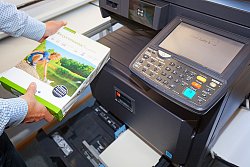 Das Foto zeigt einen großen Bürokopierer der Stadtverwaltung Lahr, bei dem das Papierfach geöffnet ist. Ein Mann mit einem karierten Hemd steht davor und ist gerade im Begriff, Papier nachzulegen. Er hat eine neue Packung Recyclingpapier in der Hand.