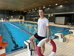(Jannes) Fachangestellter für Bäderbetriebe Azubi steht neben dem Schwimmbecken mit Rettungsring in der Hand   