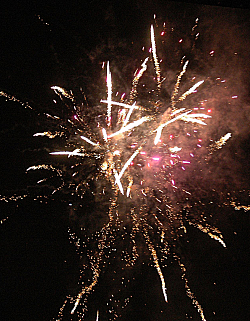 Feuerwerk in der Stadt Lahr mit explodierenden weißen Raketen im dunklen Nachthimmel. 