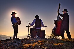 Das Foto zeigt die Rückansicht der Band auf einem Hügel