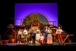 Zu sehen sind 9 Männer und Frauen, teilweise in Dirndl und Lederhose, sie stehen nebeneinander mit Sektgläsern in der Hand.