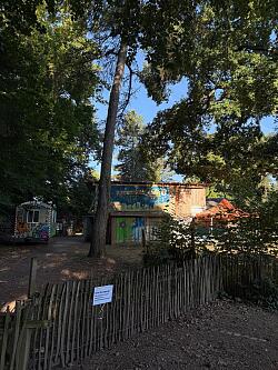 Das Foto zeigt den eingezäunten Abenteuerspielplatz samt Hütte und Bauwagen