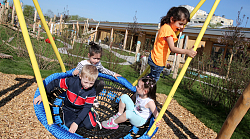 Vier Kinder sitzen in einer Kita der Stadt Lahr in einer Korbschaukel. Eines steht und nimmt Schwung, die anderen sitzen und alle jauchzen. 