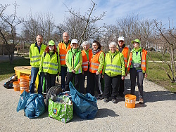 Neun Männer und Frauen mit Warnwesten und Müllsäcken