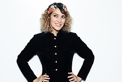 Eine Frau mit Haarband über gelocktem Haar vor weißem Hintergrund.