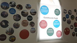 Das Bild zeigt eine Wand im Stadtmuseum Tonofenfabrik, auf der verschiedene Situationen, Gebäude und Menschen in Lahr zu sehen sind.