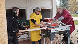 Von links: Schreiner Simon Naya Geiger steht gemeinsam mit Peter Wernet und Michael Ständer an einer Werkbank und fertigt Holzregale an.