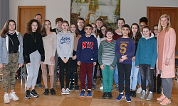 Die Schüler gruppieren sich mit ihren Lehrern und Senja Töpfer (rechts) im Sitzungssaal des Rathauses zu einem Gruppenbild und lächeln in die Kamera. 
