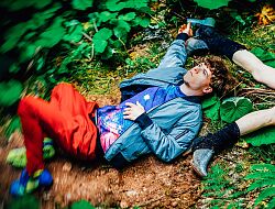 Junger Mann liegt verträumt mit offenen Augen in der Natur