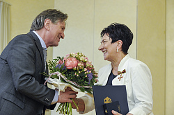 Minister Lucha (links) überreicht an Hilde Beck einen Blumenstrauß. Frau Beck trägt bereits das Verdienstkreuz am Kragen. 
